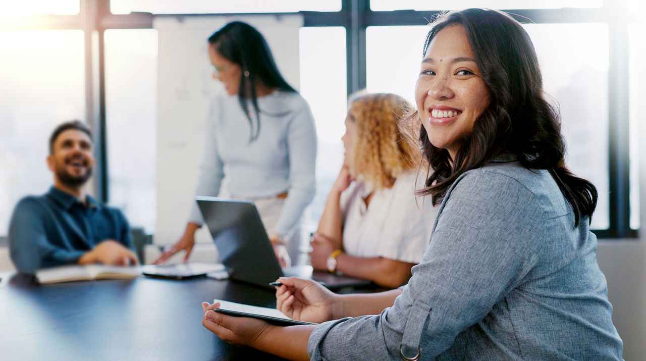 Business meeting, portrait and woman writing with team for planning, strategy and marketing idea in office. Design, collaboration and face of designer with notes for group project, vision and mission