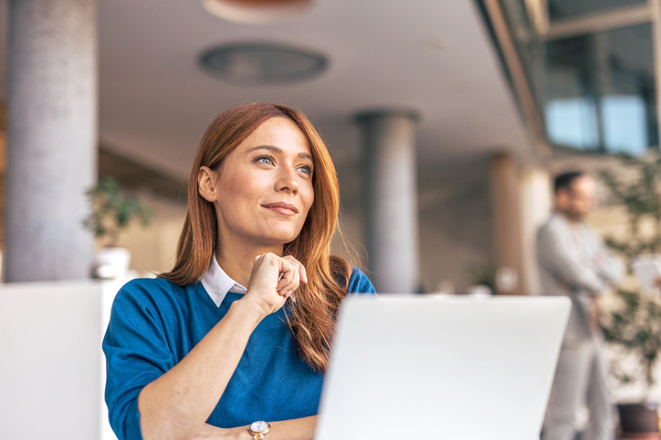 A portrait of a pensive woman sitting at a desk in the office.