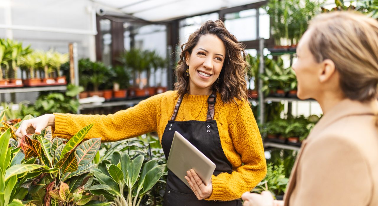 Woman at a garden center talking with an employee buying plants