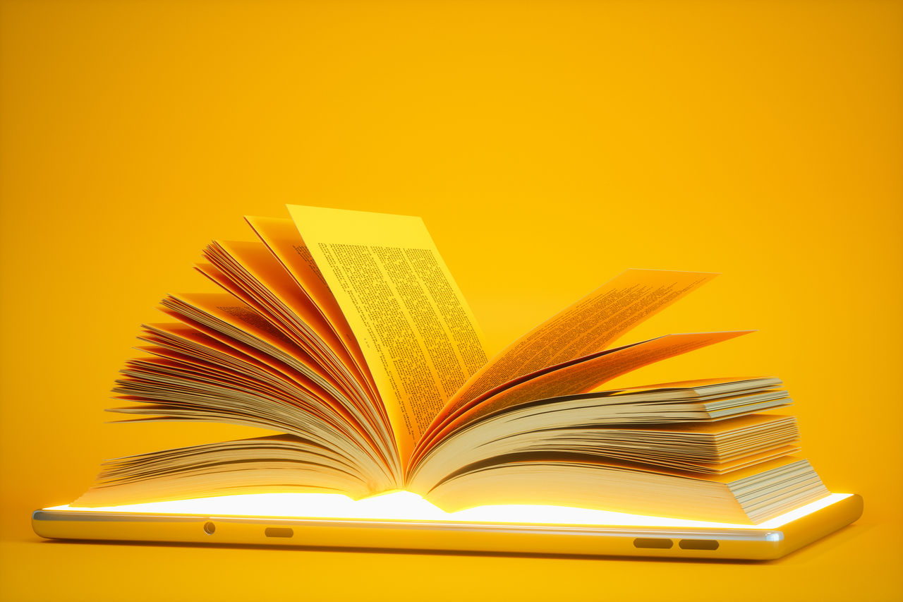 Audiobook Or E-learning Concept. Open Book On Digital Tablet With Yellow Background.